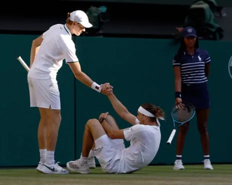 Jannik Sinner helps Alexander Zverev to his feet.