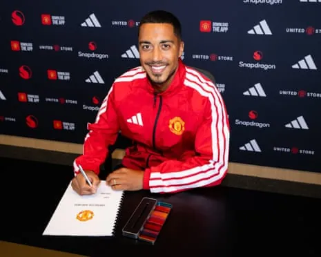 Youri Tielemans pictured in a Manchester United top signing his contract
