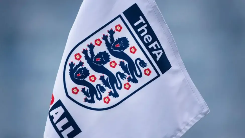 White flag featuring the FA logo - a blue shield outline featuing three horizontal blue lions and 10 small red roses